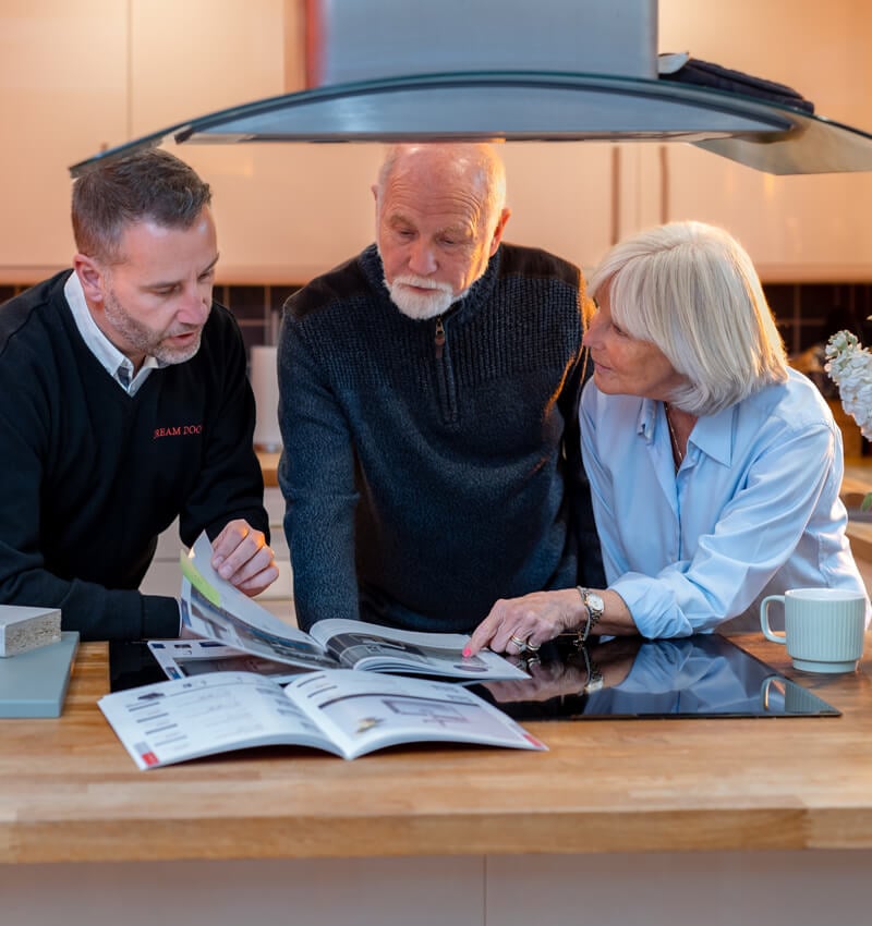 a couple sitting with a Dream Doors franchisee discussing the new design of their kitchen