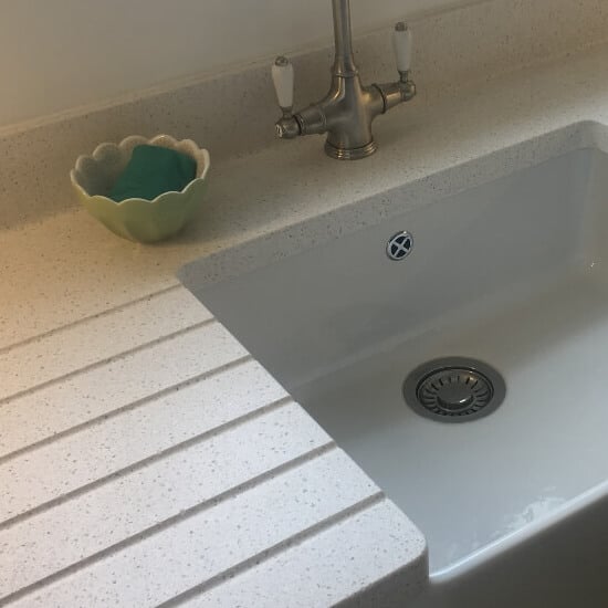 a light quartz worktop with integrated draining board and butler-style sink